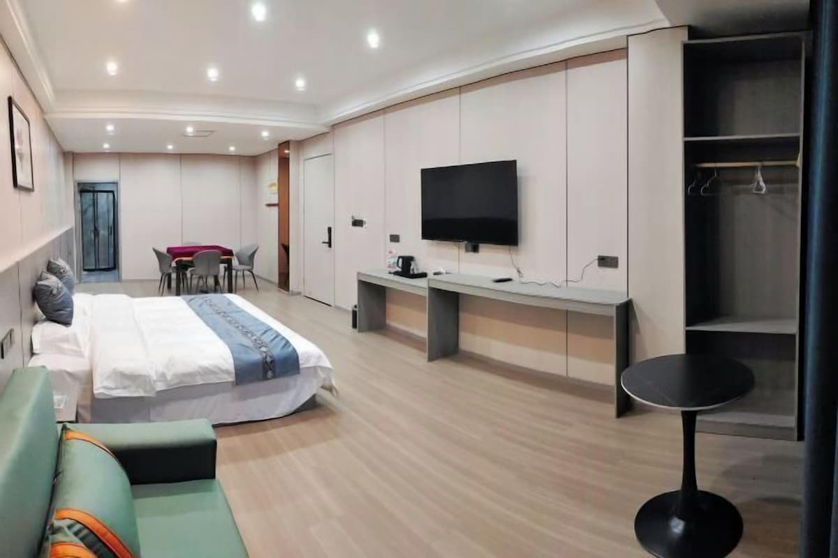 Una habitación de hotel moderna con cama, sofá, escritorio, televisor y armario.