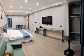 Una habitación de hotel moderna con cama, sofá, escritorio, televisor y armario.