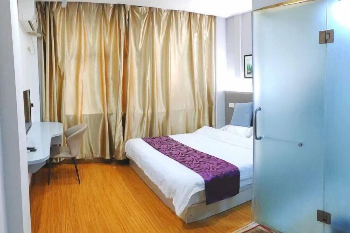 A hotel room with a bed, a desk, a chair, and a wardrobe.