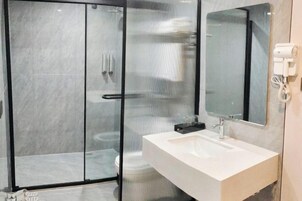 Un baño moderno con ducha de vidrio, lavamanos blanco y espejo.