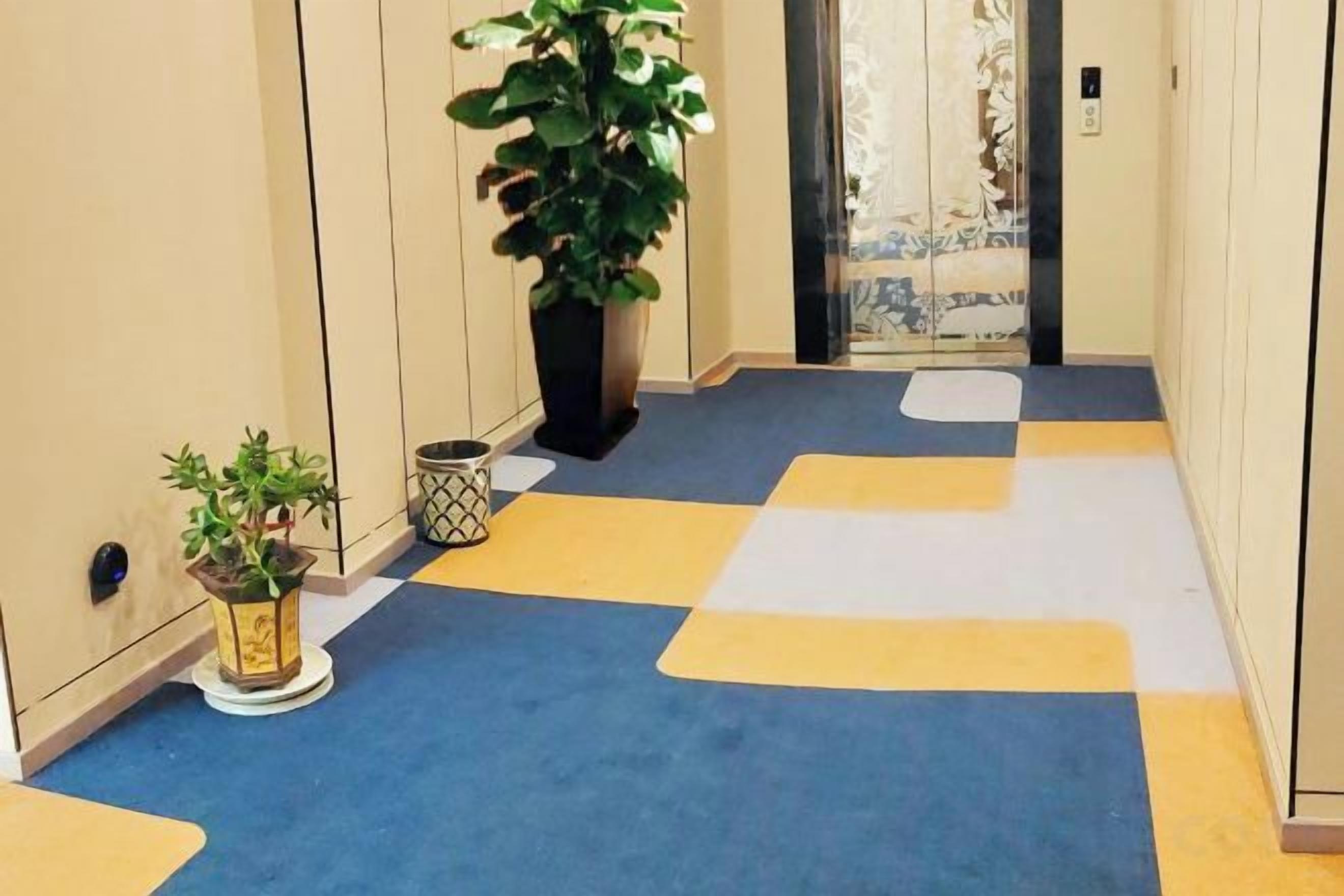 A hallway with a checkered floor pattern, a potted plant, and a door with a curtain.
