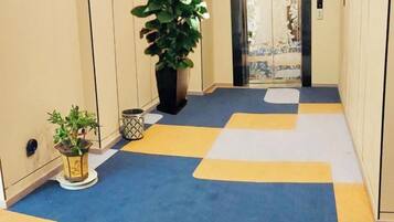 A hallway with a checkered floor pattern, a potted plant, and a door with a curtain.