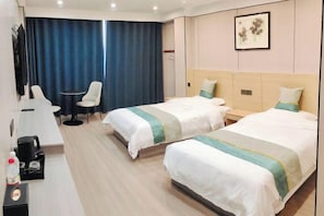 Habitación de hotel con dos camas, un escritorio, una silla y un ventanal con cortinas.