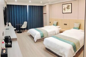 A hotel room with two beds, a desk, a chair, and a large window with curtains.