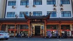 Un edificio con una entrada de arquitectura tradicional china, unidades de aire acondicionado y scooters estacionados.