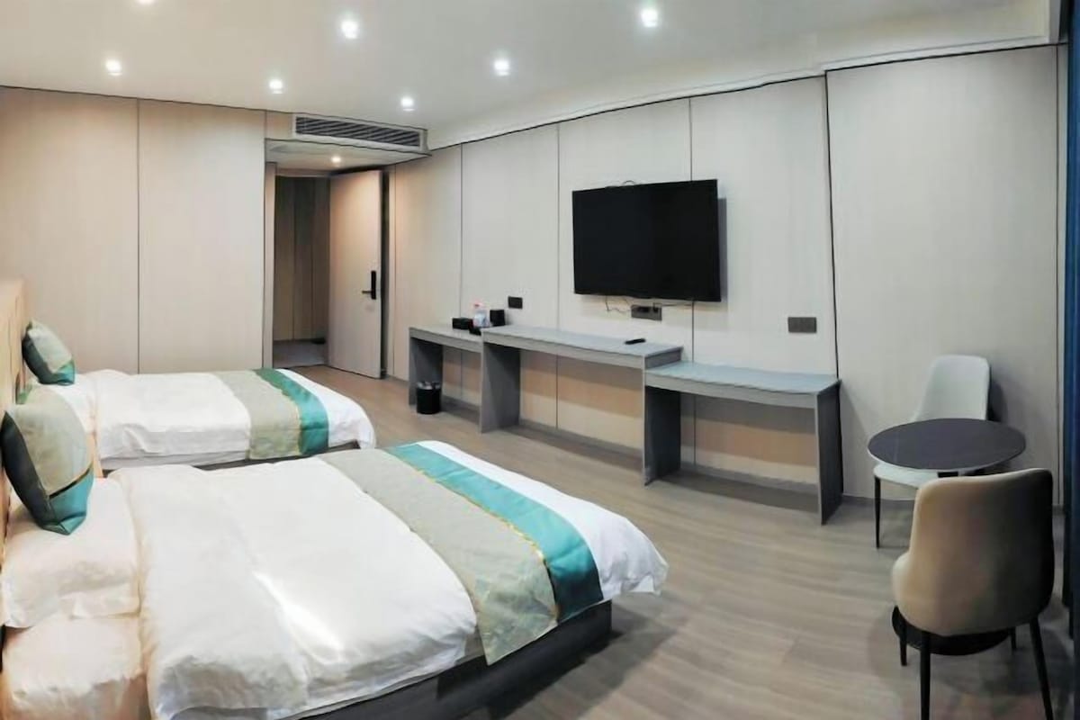 Una habitación de hotel con dos camas, televisión, escritorio y silla.