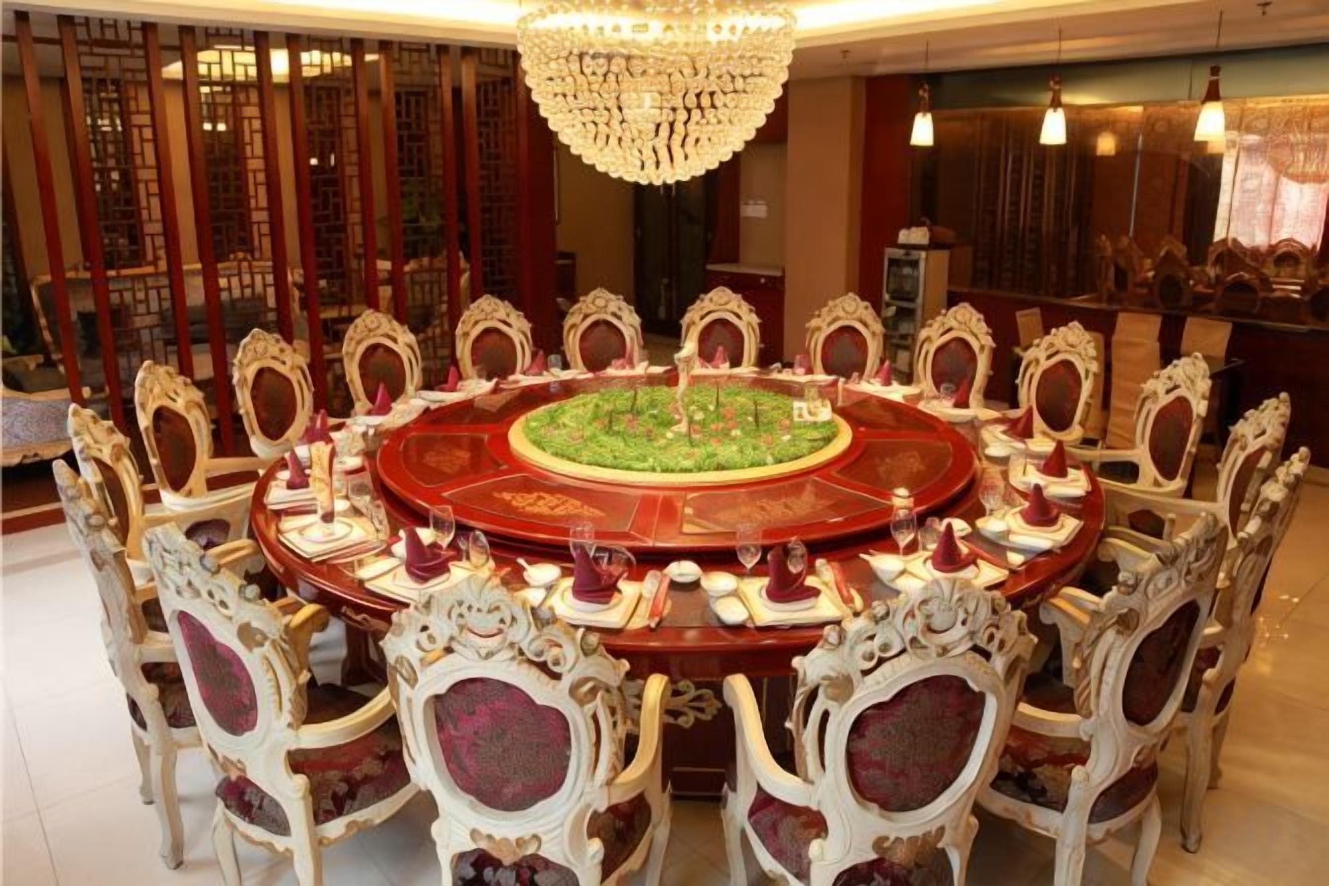 A round dining table with ornate chairs, a central floral arrangement, and a chandelier.