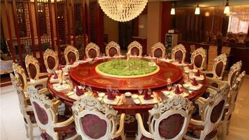 A round dining table with ornate chairs, a central floral arrangement, and a chandelier.