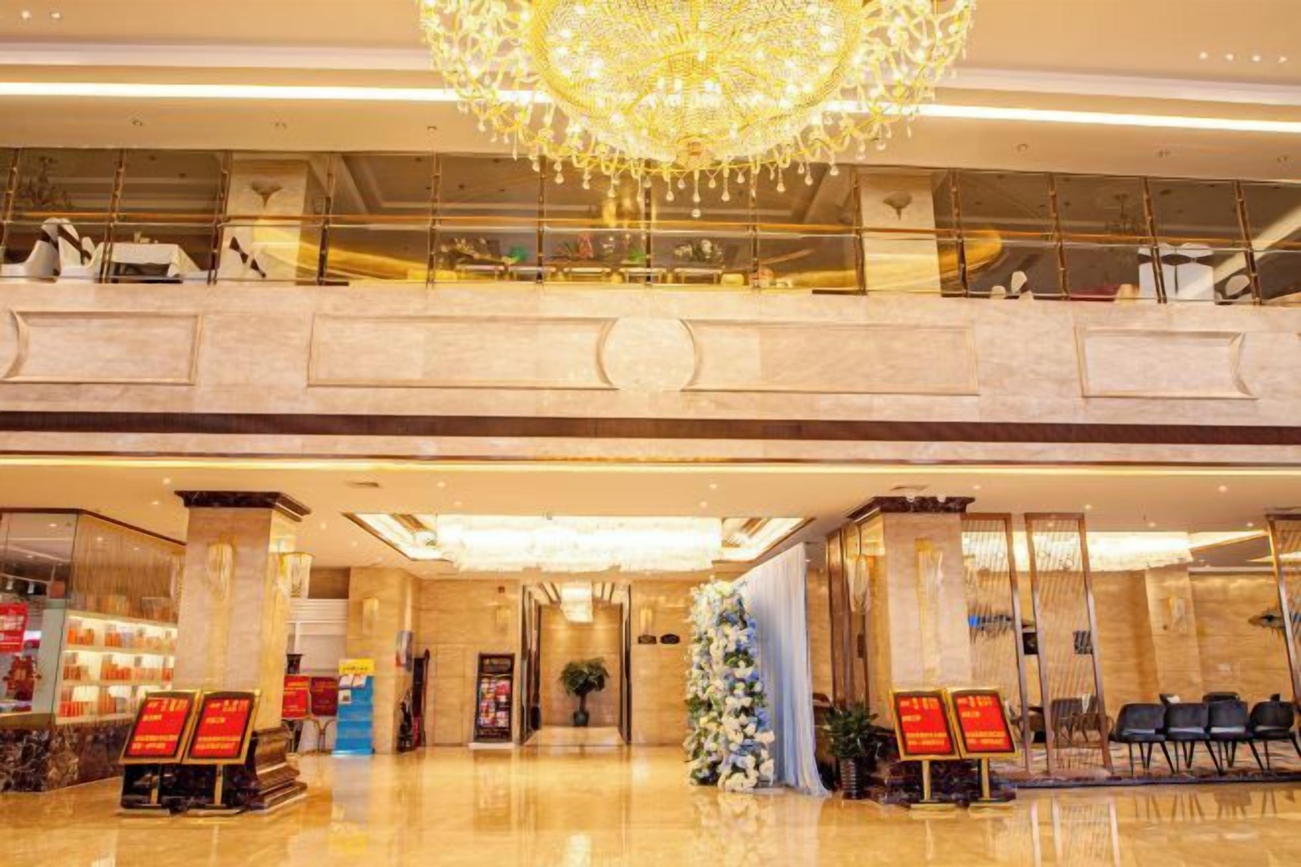 A hotel lobby with a chandelier, a reception desk, and a seating area.