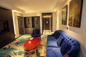 A modern living room with a red table, blue sofa, and abstract wall art. - Shuyi International Hotel (Shucheng)