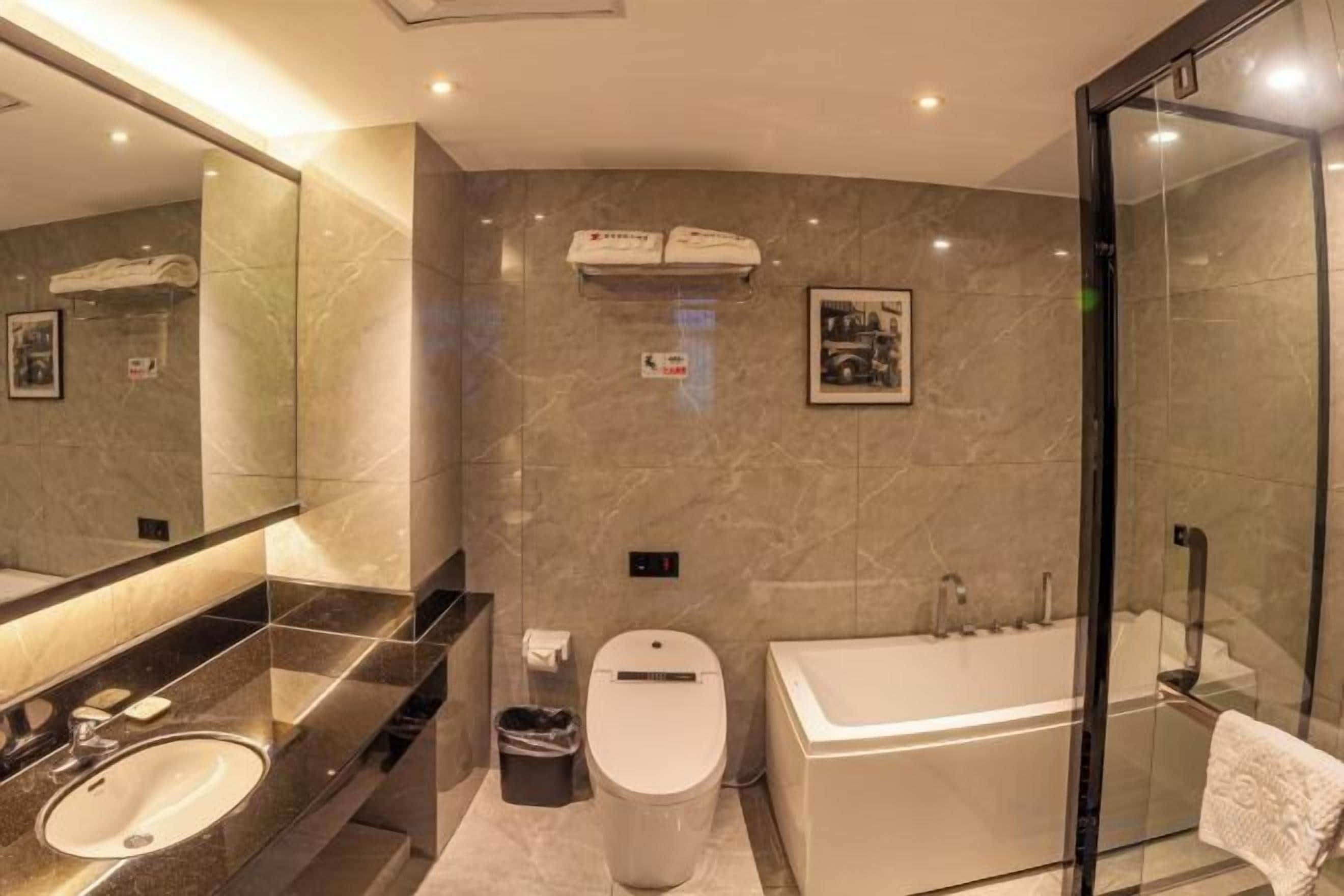 Un baño moderno con cabina de ducha de vidrio, una bañera, un inodoro y un lavabo con tocador.