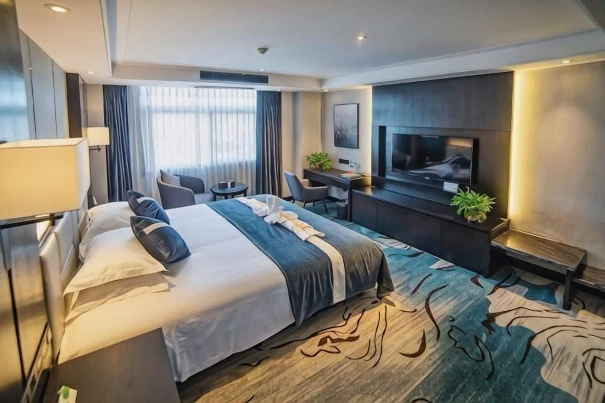 Habitación de hotel con una cama grande, un escritorio, un televisor y una zona de estar.