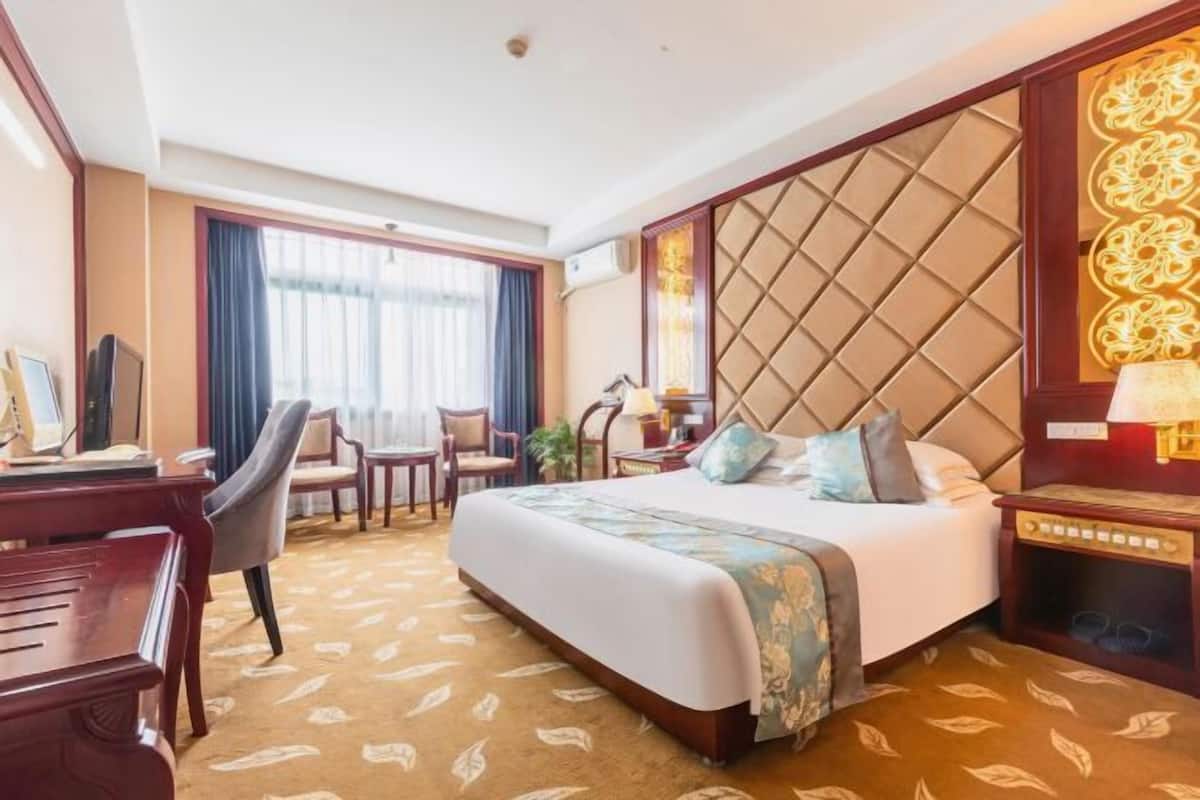 Una habitación de hotel con cama, escritorio, silla y ventana.