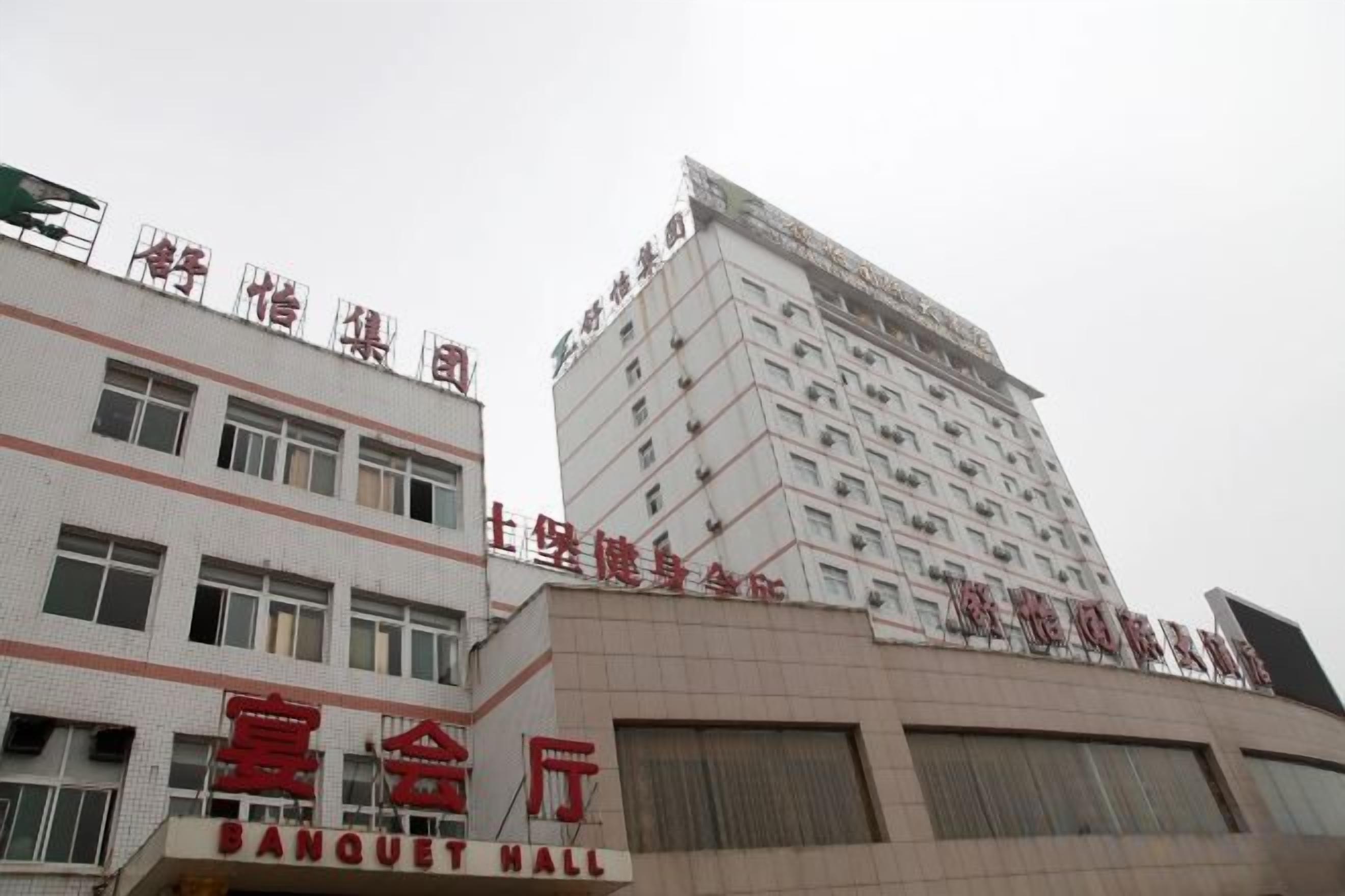 Un immeuble à plusieurs étages portant les enseignes « SALLE DE BANQUET » et « HÔTEL ».