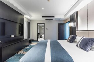 Una habitación de hotel moderna con una cama grande, un televisor de pantalla plana y un vestidor.