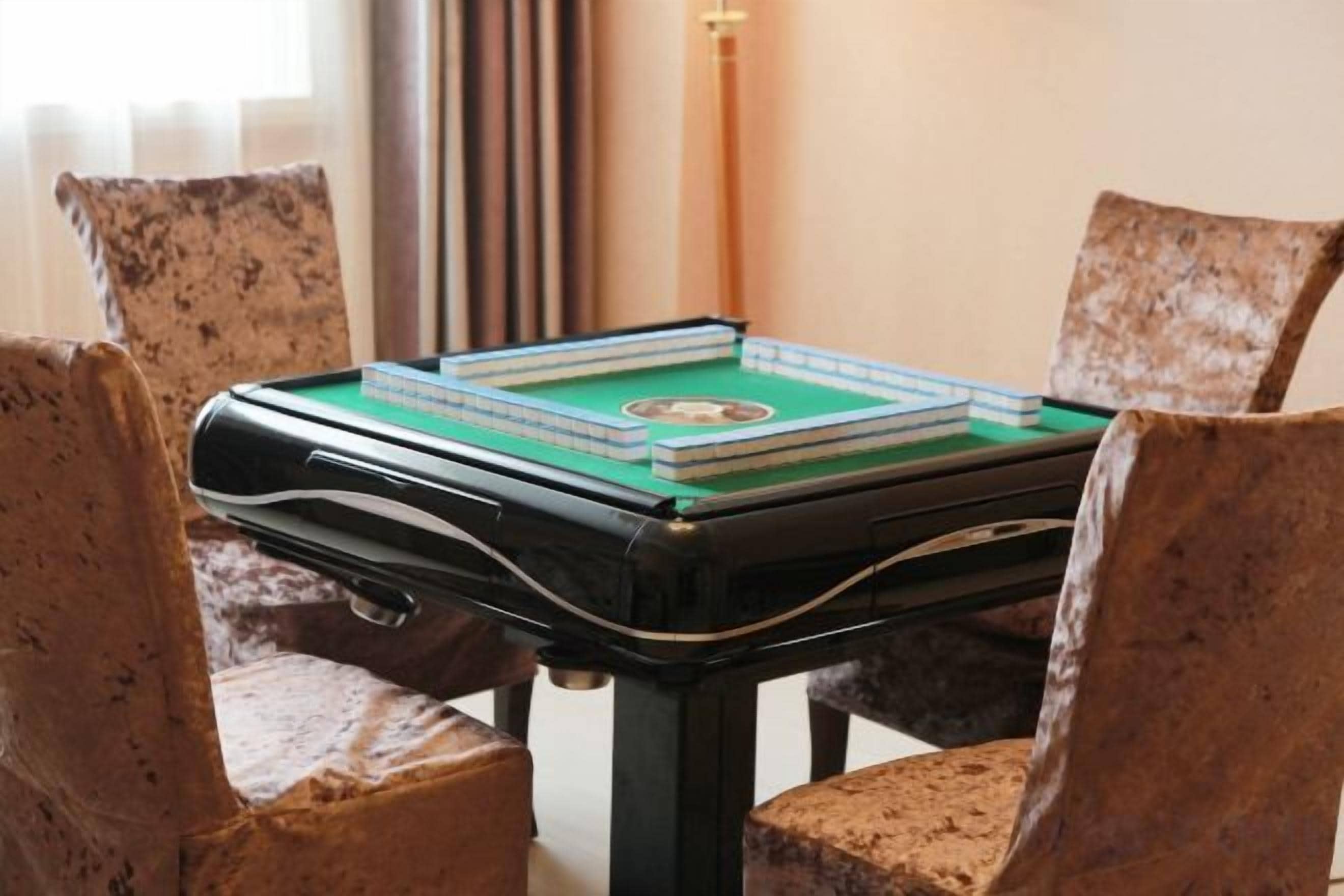 A pool table with a green felt surface, surrounded by four chairs with a speckled pattern.