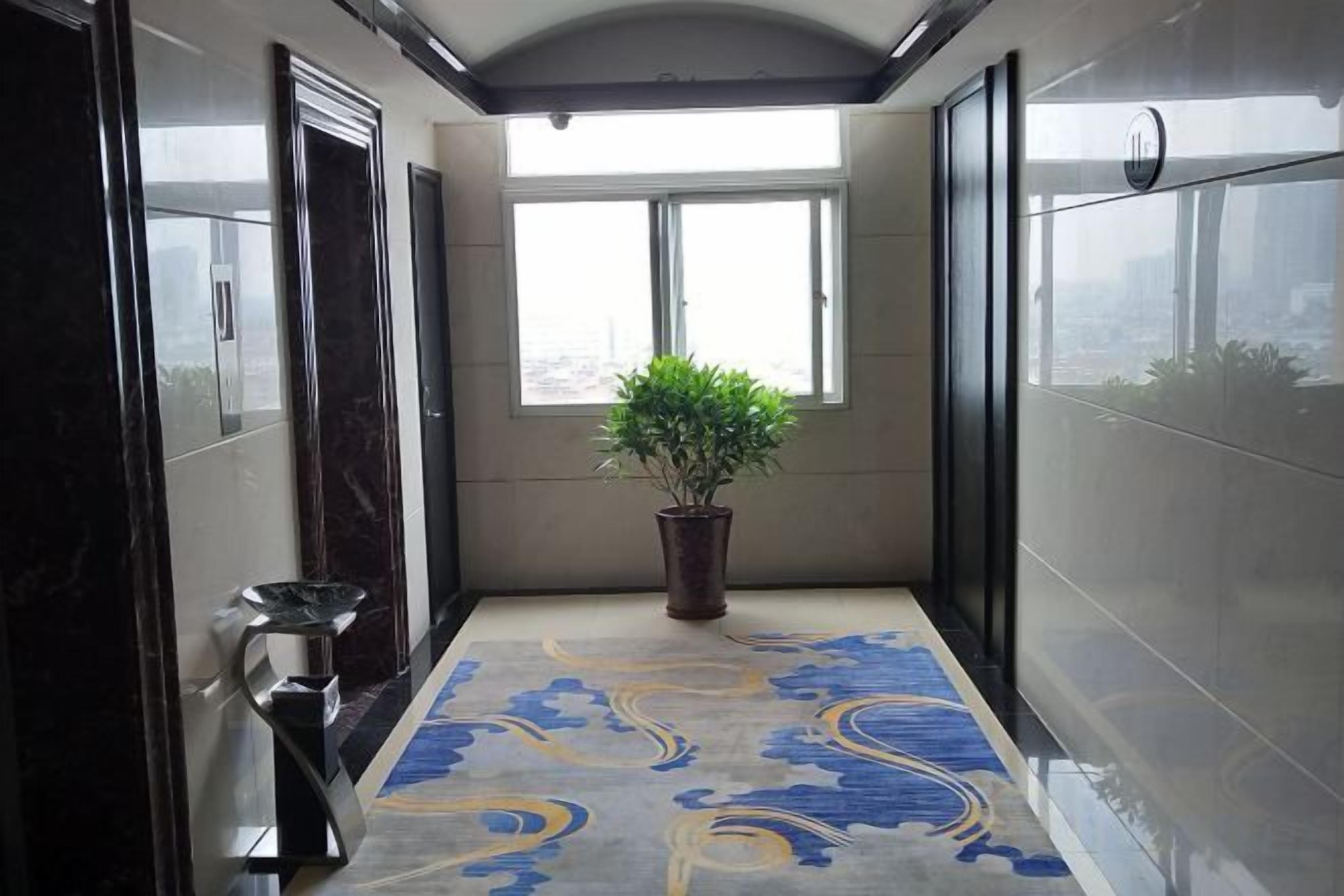 A corridor with a potted plant, a marble floor, and a view through a window.