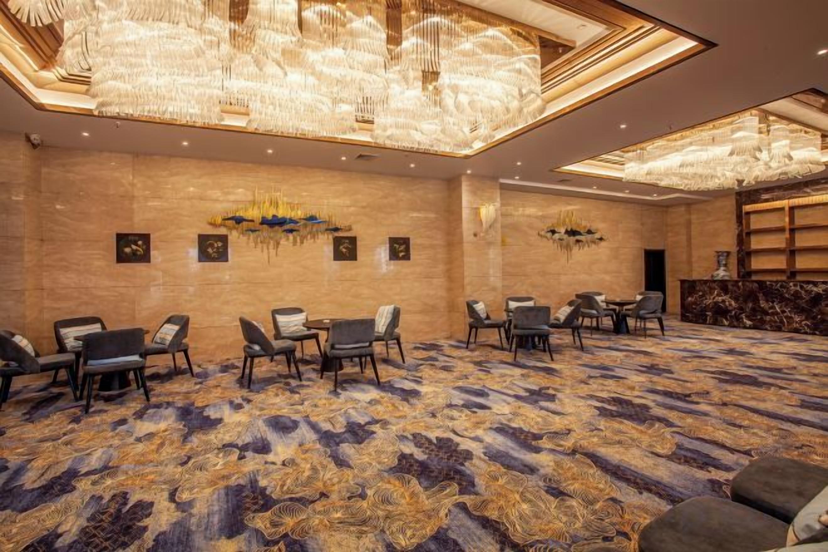 A conference room with a patterned carpet, tables, chairs, and a chandelier.