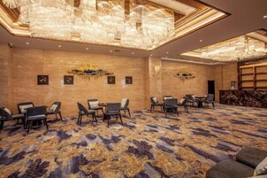 Un salón de conferencias con alfombra estampada, mesas, sillas y una araña.