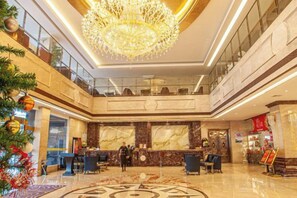 A spacious lobby with a grand chandelier, marble reception desk, and a high ceiling. - Shuyi International Hotel (Shucheng)