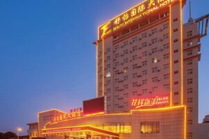 Un hotel de varios pisos con letreros iluminados y una entrada destacada.