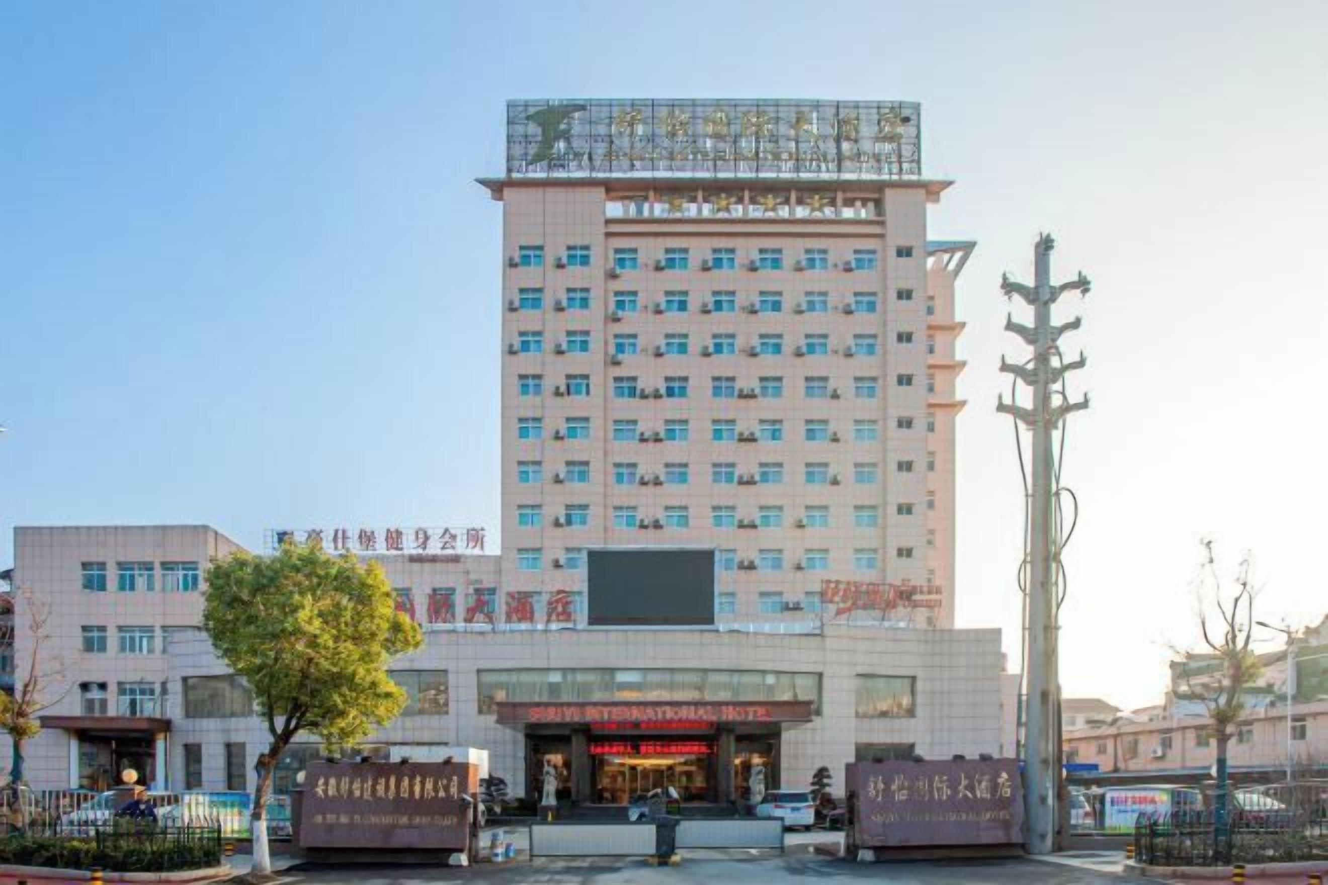 A multi-story hotel with a central entrance, multiple floors, and a flat roof.