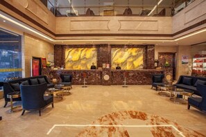 A hotel lobby with a reception desk, seating area, and a large marble wall. - Shuyi International Hotel (Shucheng)