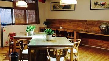 A dining area with a wooden table and chairs, a potted plant, and a wooden bench.