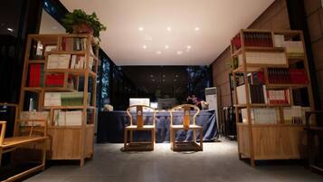 A room with a wooden bookshelf, two chairs, a table, and a plant.