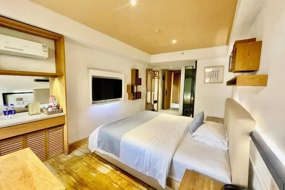 A bedroom with a bed, bedside tables, a TV, and a window.