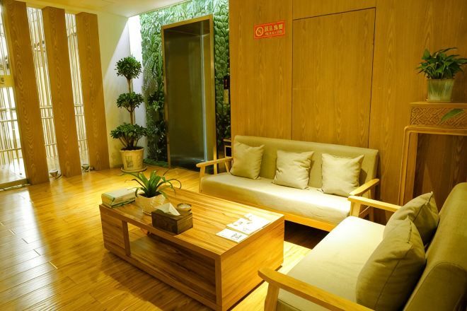 A reception area with a wooden floor, a sofa, a coffee table, and a reception desk.