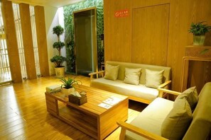 A reception area with a wooden floor, a sofa, a coffee table, and a reception desk. - Wending Yaxuan Hotel (Zhengzhou)