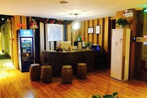 Una zona de recepción con piso de madera, un mostrador de recepción, un refrigerador y una máquina expendedora.