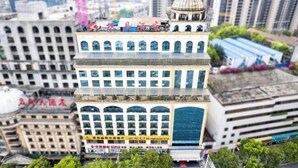 Un edificio de varios pisos con una cúpula central, ventanas grandes y techo plano.