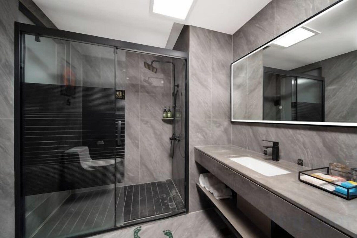 Une salle de bain moderne avec une douche à parois de verre, un grand miroir et un meuble-lavabo.