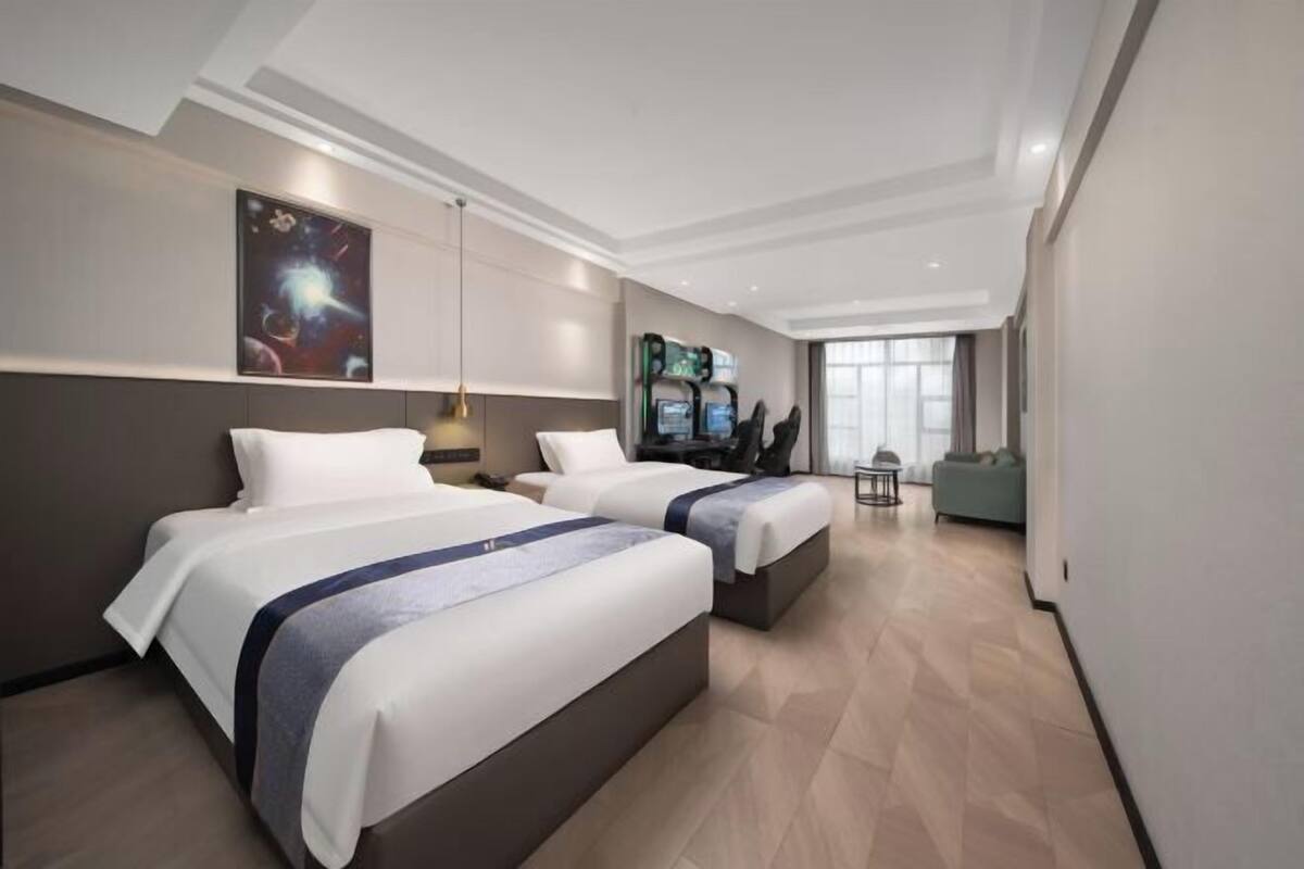 Una habitación de hotel con dos camas, televisión, escritorio y sofá.