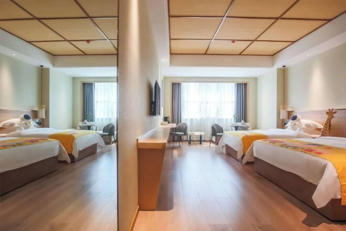 Una habitación de hotel con dos camas, un escritorio, sillas y una televisión.