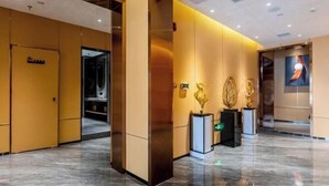 Un moderno vestíbulo de hotel con piso de mármol, una recepción y una gran obra de arte en la pared.