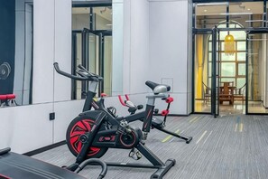 Un gimnasio con equipo de ejercicio, un espejo y una puerta de vidrio que da a un comedor.