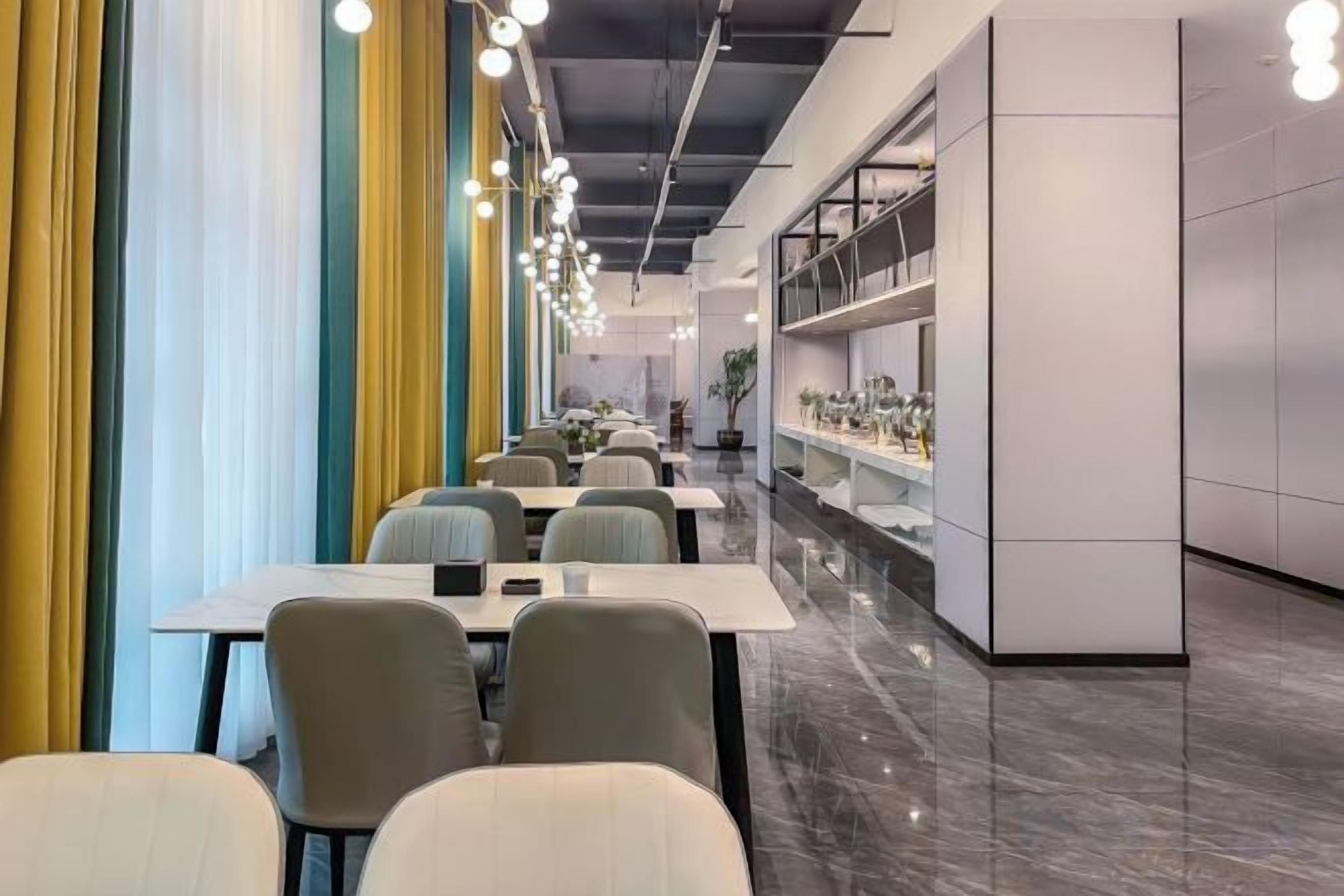 Un área de comedor moderna con mesas y sillas, una barra alargada con exhibición, y vista al salón.