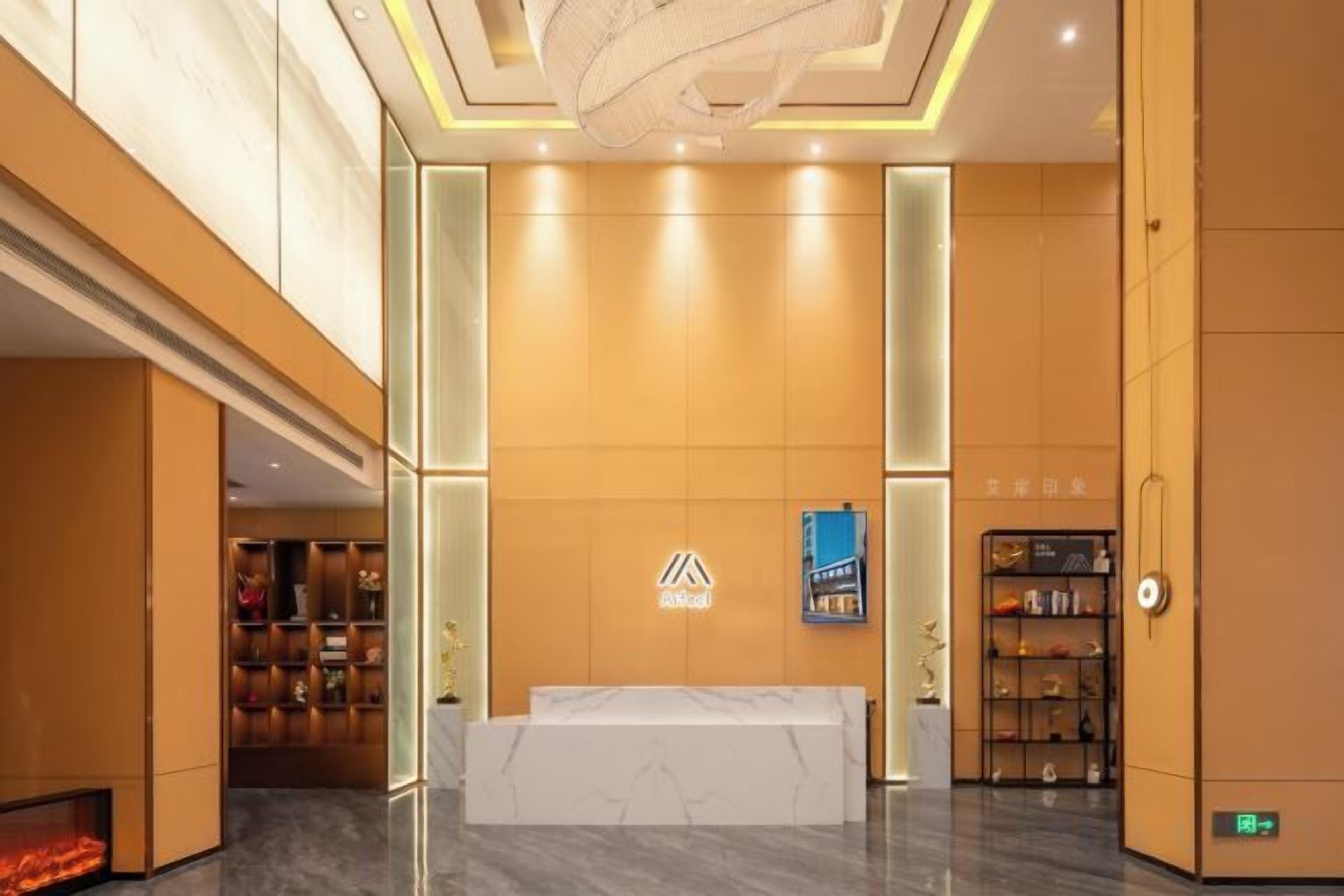 Zona d'entrada d'un hotel, amb una recepció, un senyal vertical i una estanteria.