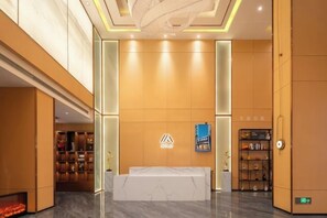 Een hotel receptie met een receptiebalie, een bord aan de muur en een boekenplank.