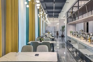 Een modern restaurantinterieur met lange tafels, stoelen en hangende lampen.