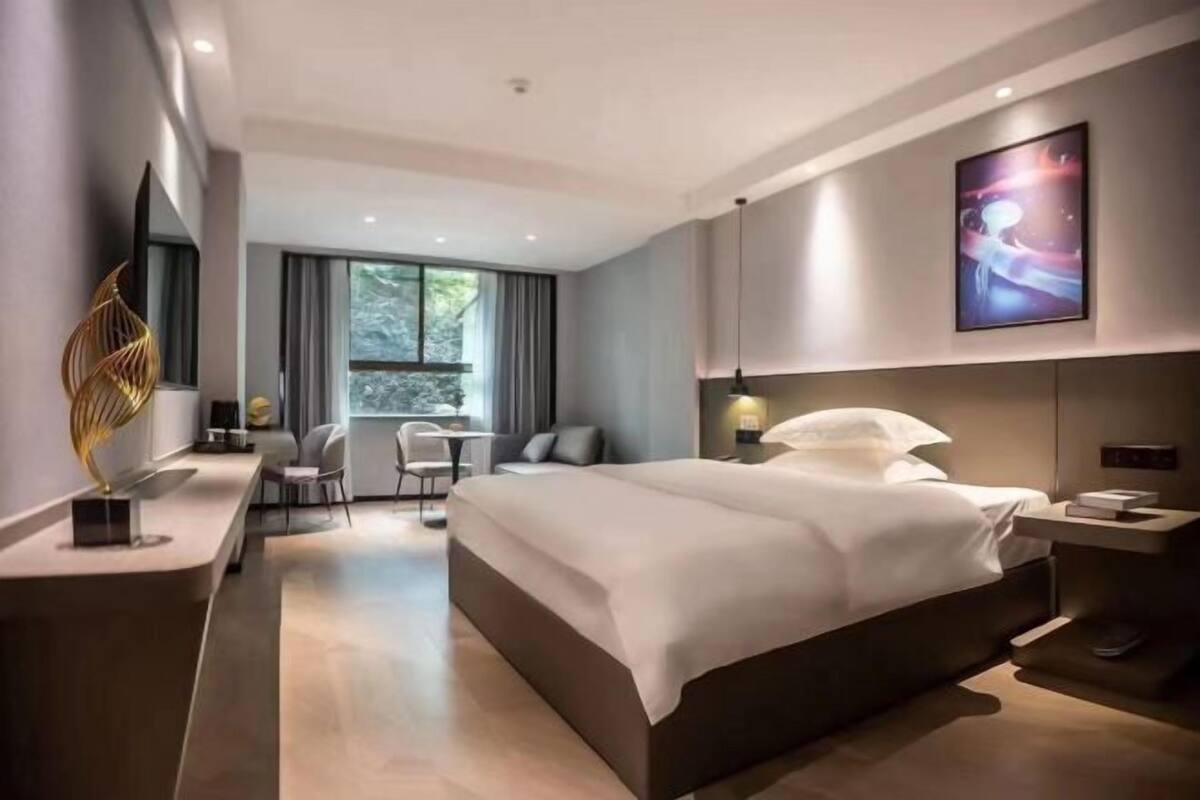 Una habitación de hotel moderna con una cama grande, mesitas de noche, un escritorio y una silla.