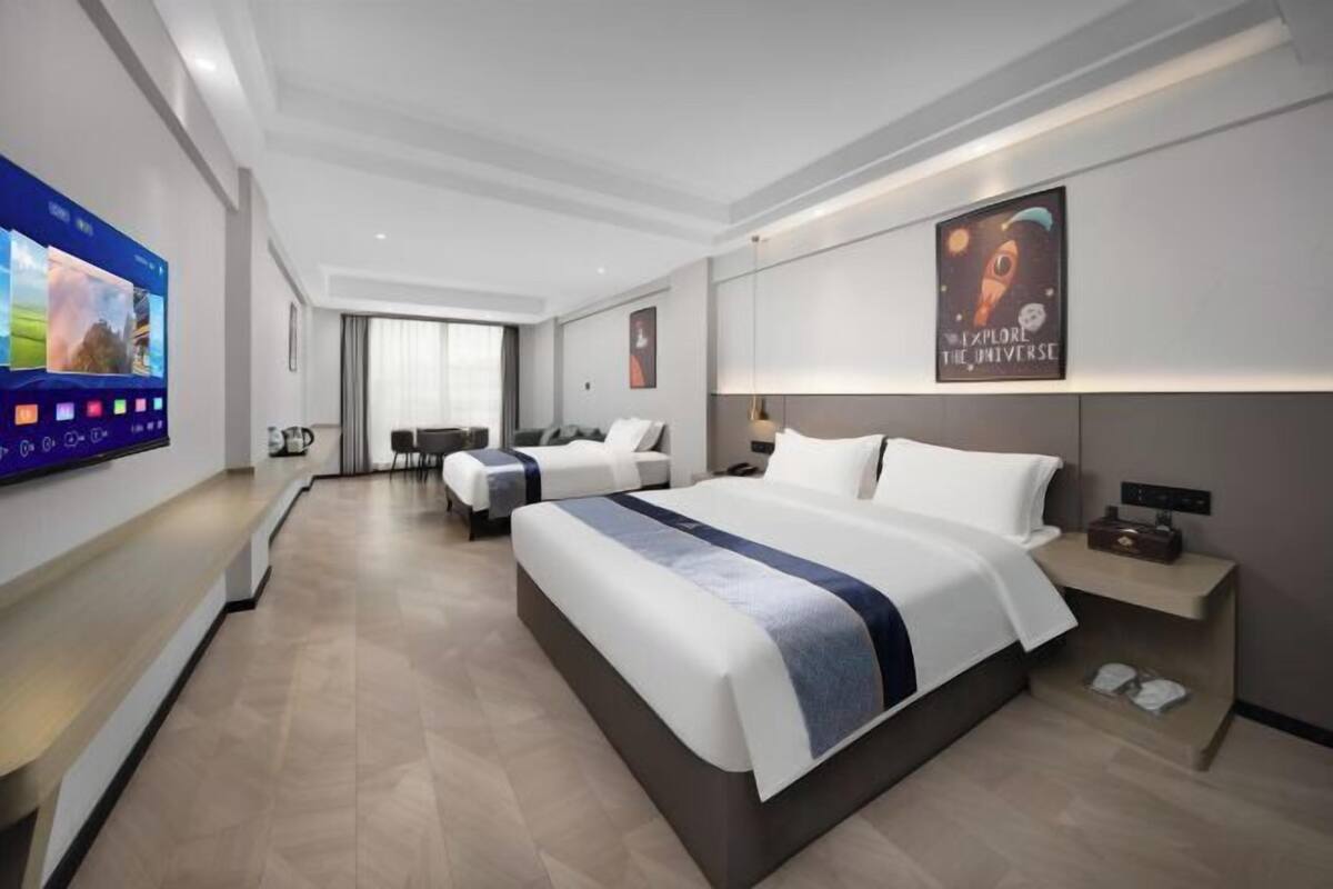 Una habitación de hotel moderna con una cama grande, televisor, escritorio y zona de estar.