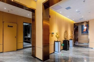 Un vestíbulo de hotel con piso de mármol, una recepción y un ascensor empotrado en la pared.