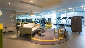 Ein modernes Fitnessstudio mit Trainingsgeräten, einer Couch und einem Spiegel.