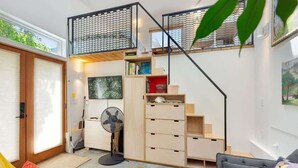 Ein modernes Loft mit Treppe, Ventilator und Bücherregal.