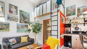 Eine moderne Wohnung mit einer offenen Küche im Loft-Stil, einem Essbereich und einem Wohnzimmer mit Sofa und Sesseln.