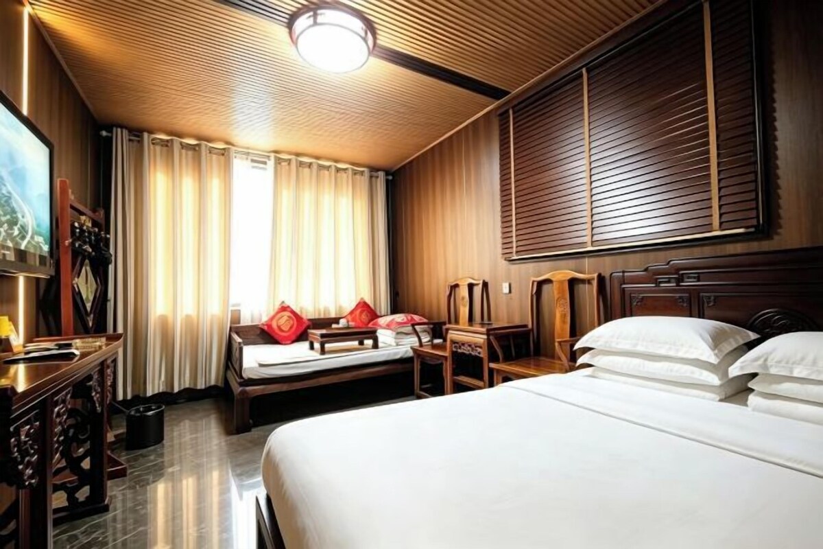 A hotel room with a large bed, a desk, and a view of the outdoors.